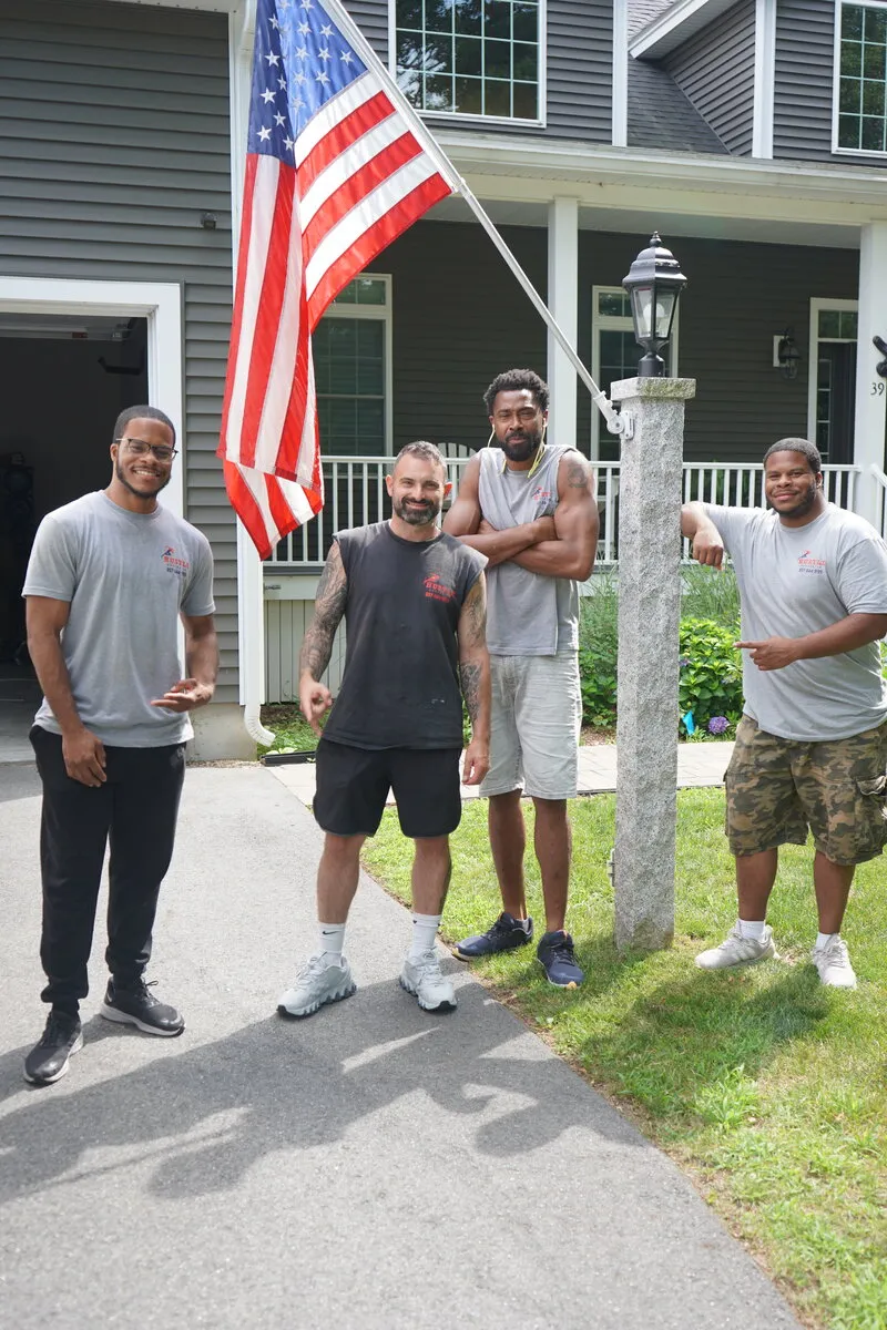 Four members of the Hustle Moving Company crew outside a customer's home