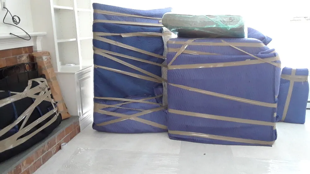 Furniture wrapped in blue moving blankets and taped, ready for the truck